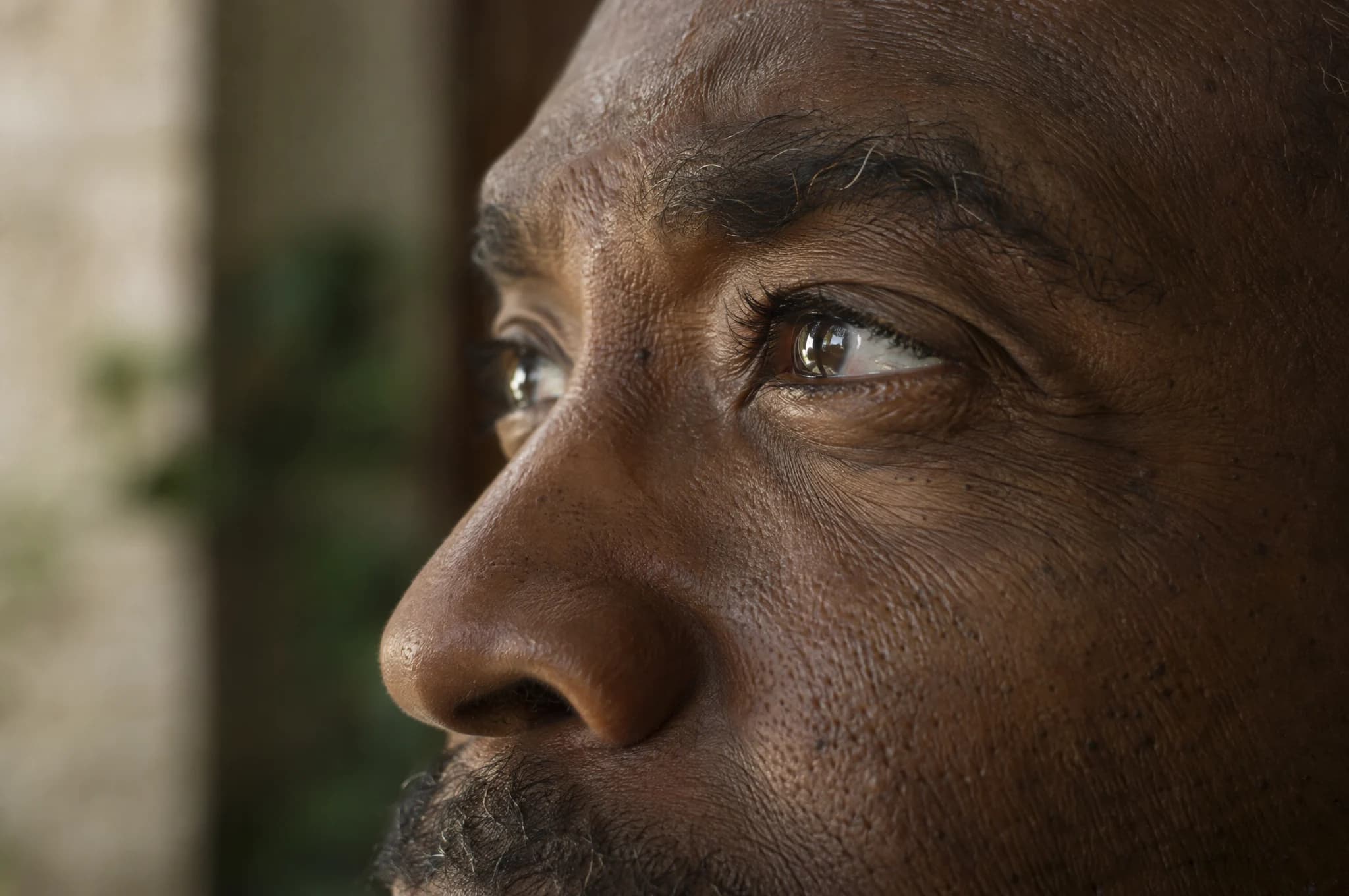 An older man's eye and cheek in profile, looking toward daylight